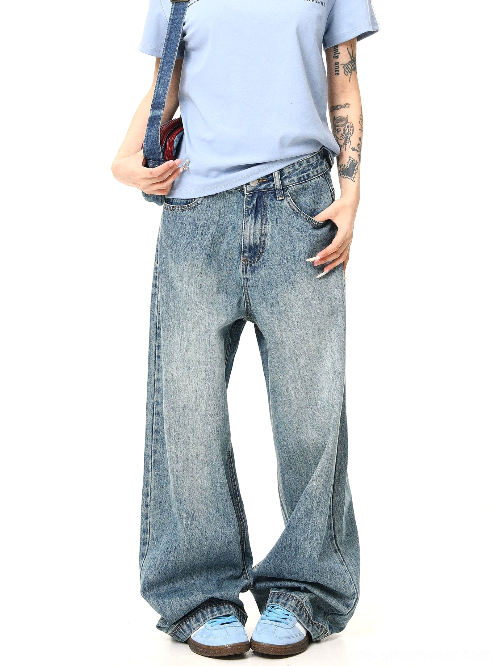 Front full-body view of women wearing retro washed blue baggy wide-leg jeans with a light blue T-shirt and blue sneakers