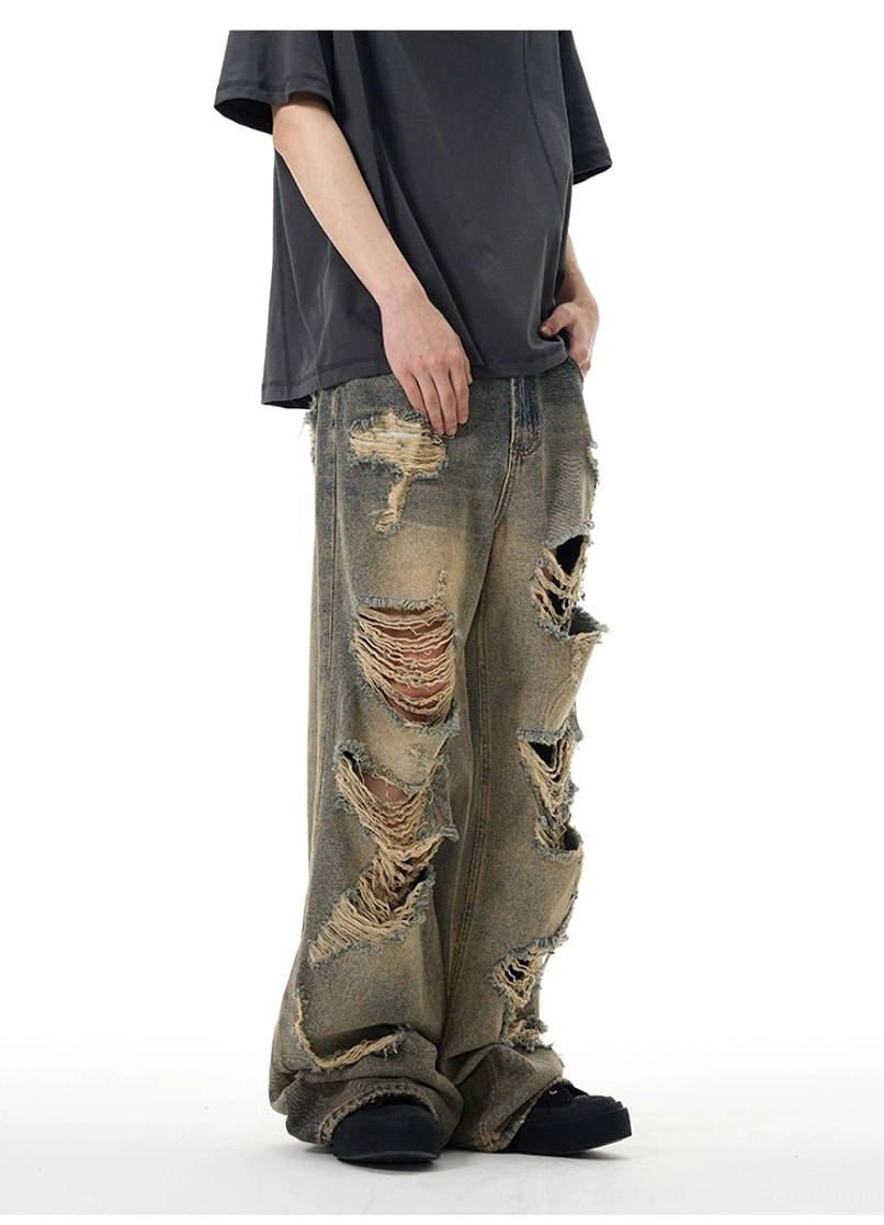 Side front view of retro washed blue ripped jeans with asymmetrical distressed details and oversized streetwear fit