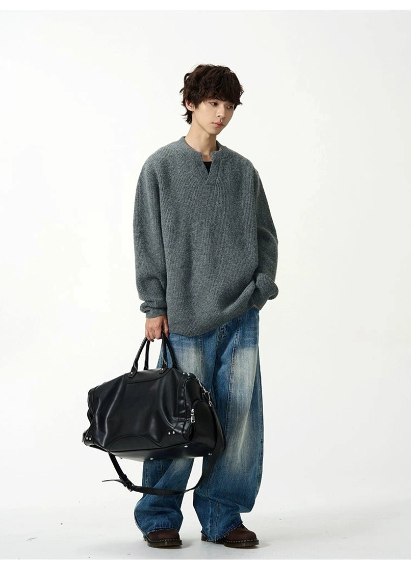 Retro blue wide-leg denim jeans with a structured front seam styled with grey knitwear and a black leather duffle bag