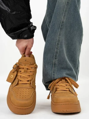 Wheat yellow retro nubuck platform skate sneakers shown from the front and worn with loose blue jeans and a black windbreaker