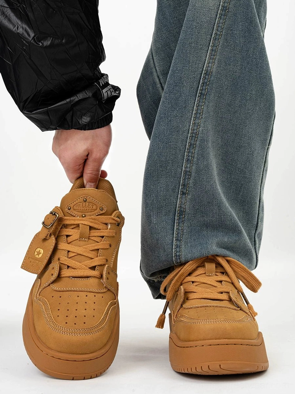 Wheat yellow retro nubuck platform skate sneakers shown from the front and worn with loose blue jeans and a black windbreaker