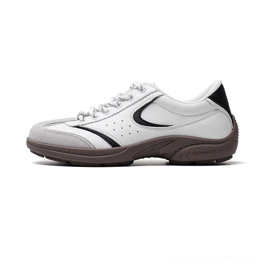 White black and brown retro court sneakers with perforated leather upper curved side stripes and warm rubber outsole shown in a left side three quarter studio view