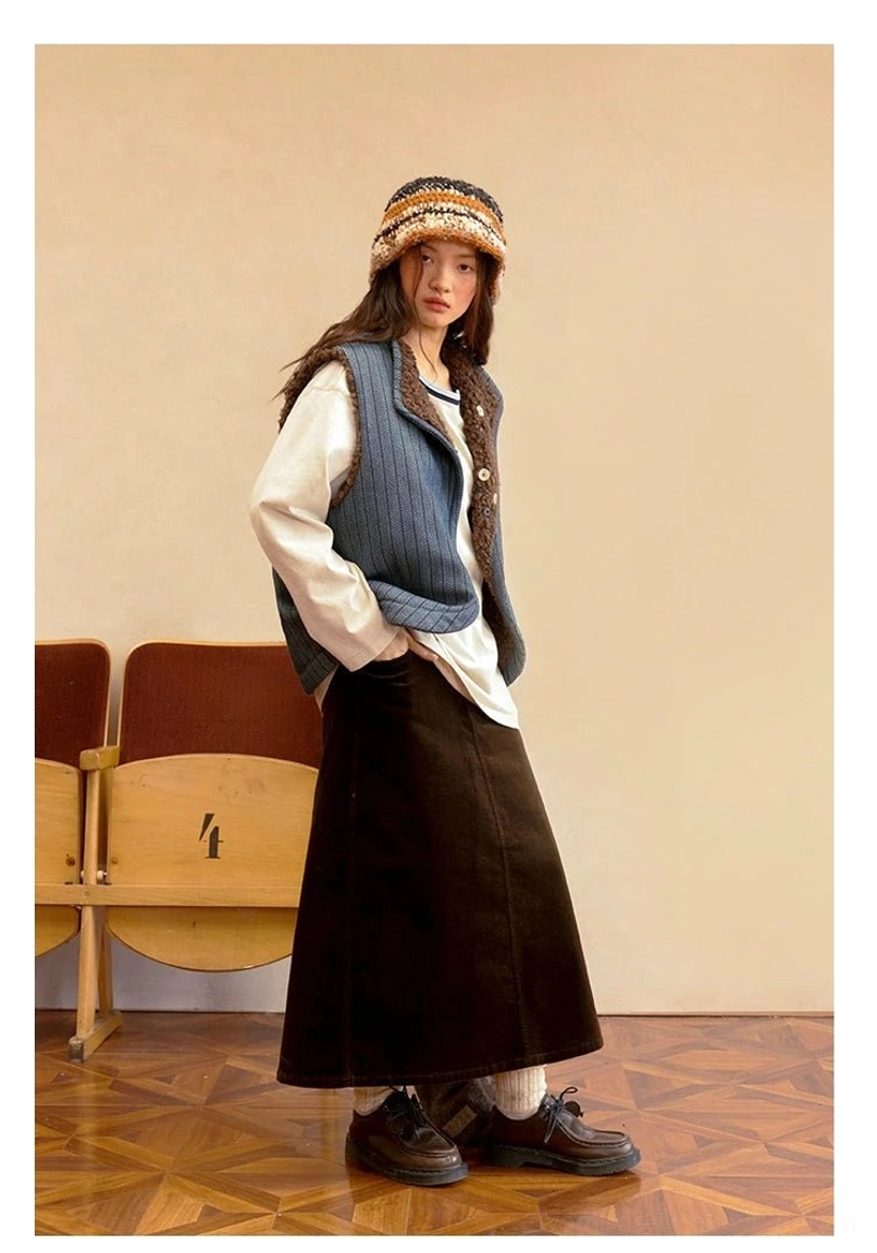 Three-quarter view of blue denim reverse side of reversible sherpa vest with hands in pockets in a vintage theater setting