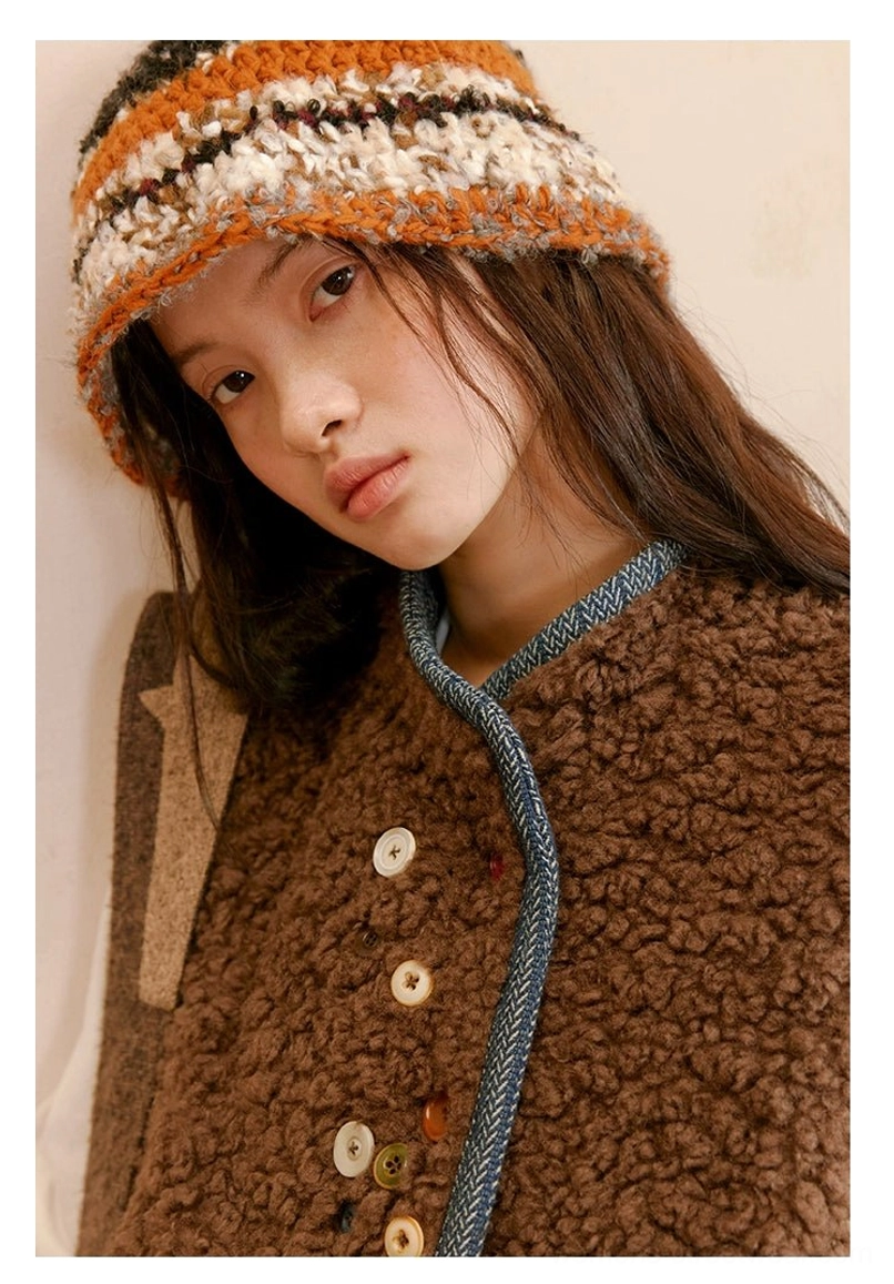 Close-up of stand collar, plush brown sherpa fabric, blue braided contrast trim, and assorted decorative buttons on reversible vest