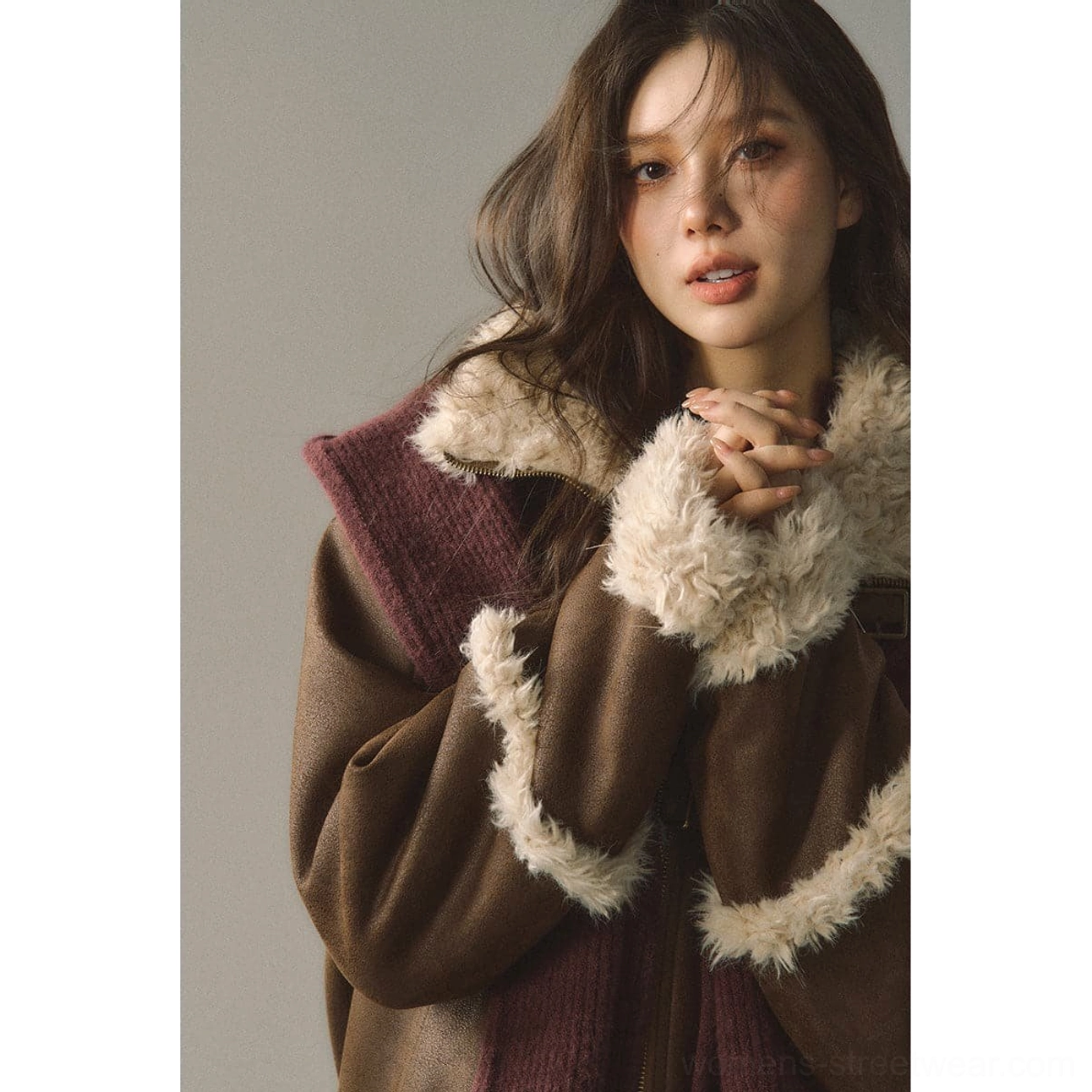 Upper-body view of a reversible suede shearling jacket showing brown and wine contrast panels, cream cuffs, and plush trim details