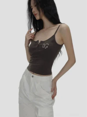 Dark brown ribbed spaghetti strap camisole with Henley button neckline and XO chest embroidery styled with white wide leg trousers