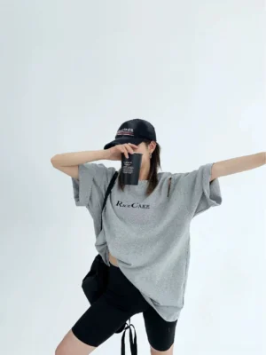 Heather gray oversized RICE CAKE graphic tee with zip shoulder cutout styled with a black crossbody bag