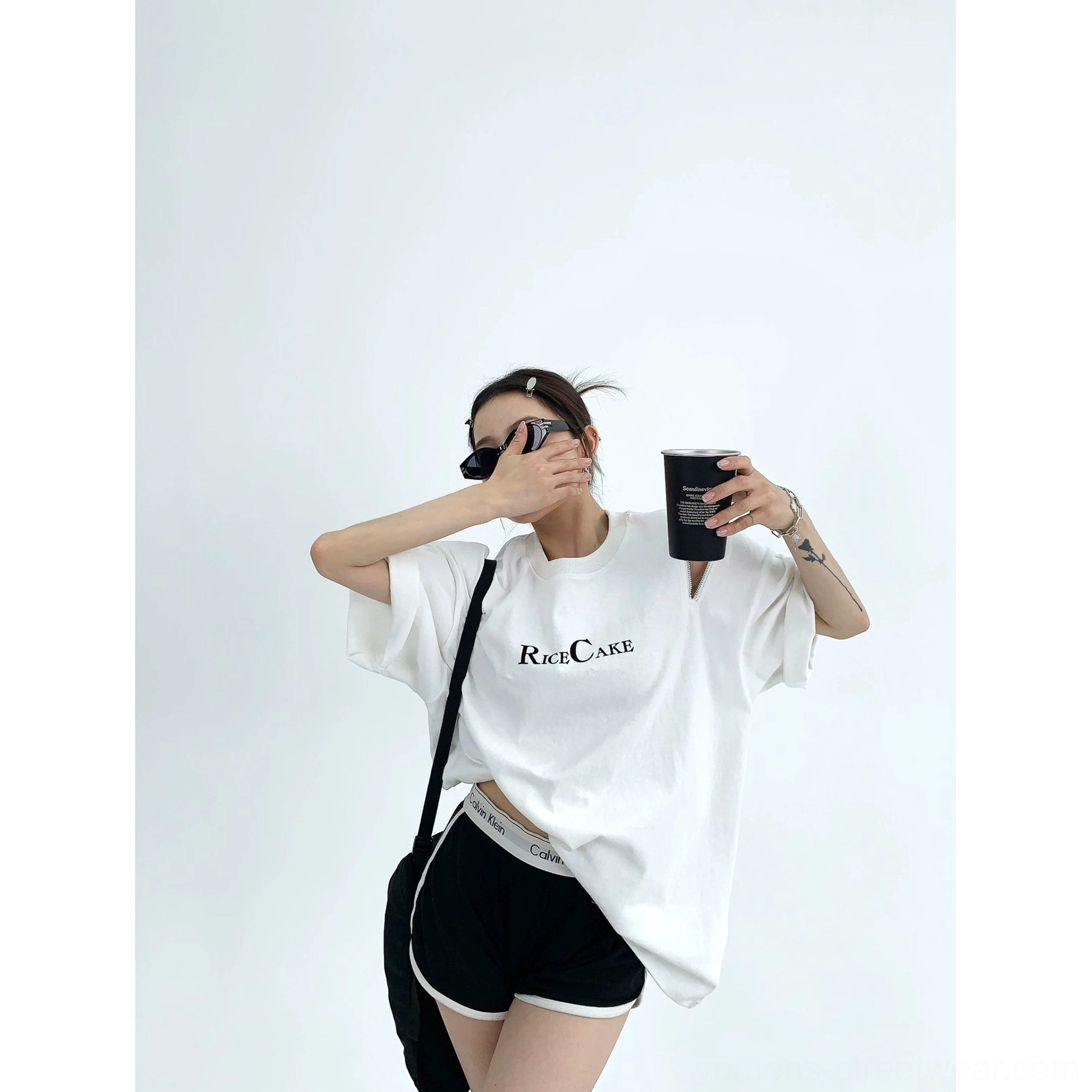 White RICE CAKE oversized zip shoulder graphic tee styled with black biker shorts and a crossbody bag