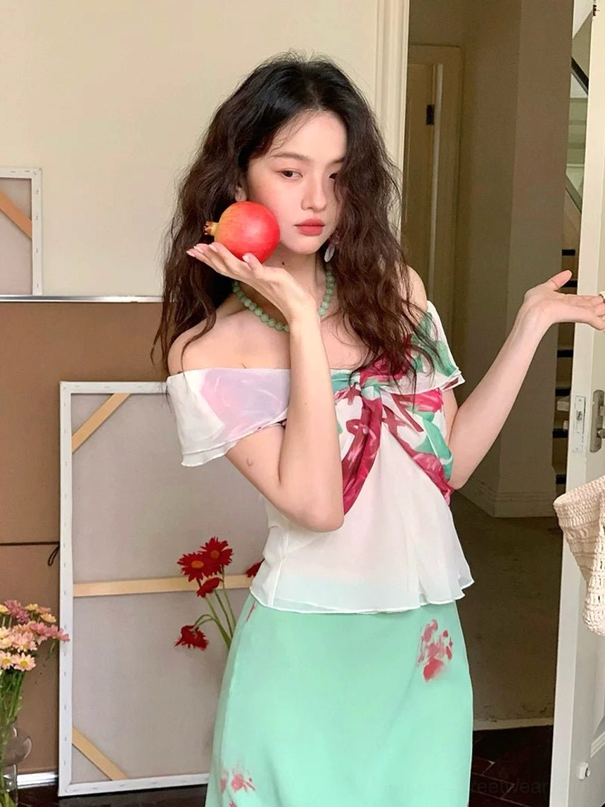 Close front view of white ruffled off-shoulder blouse featuring a large floral bow and feminine cropped peplum silhouette