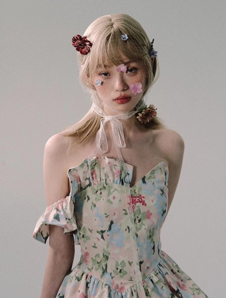 Close-up of a romantic watercolor floral mini dress with lace-up neck detail, ruffled sleeve edges, sweetheart bodice, and feminine streetwear styling