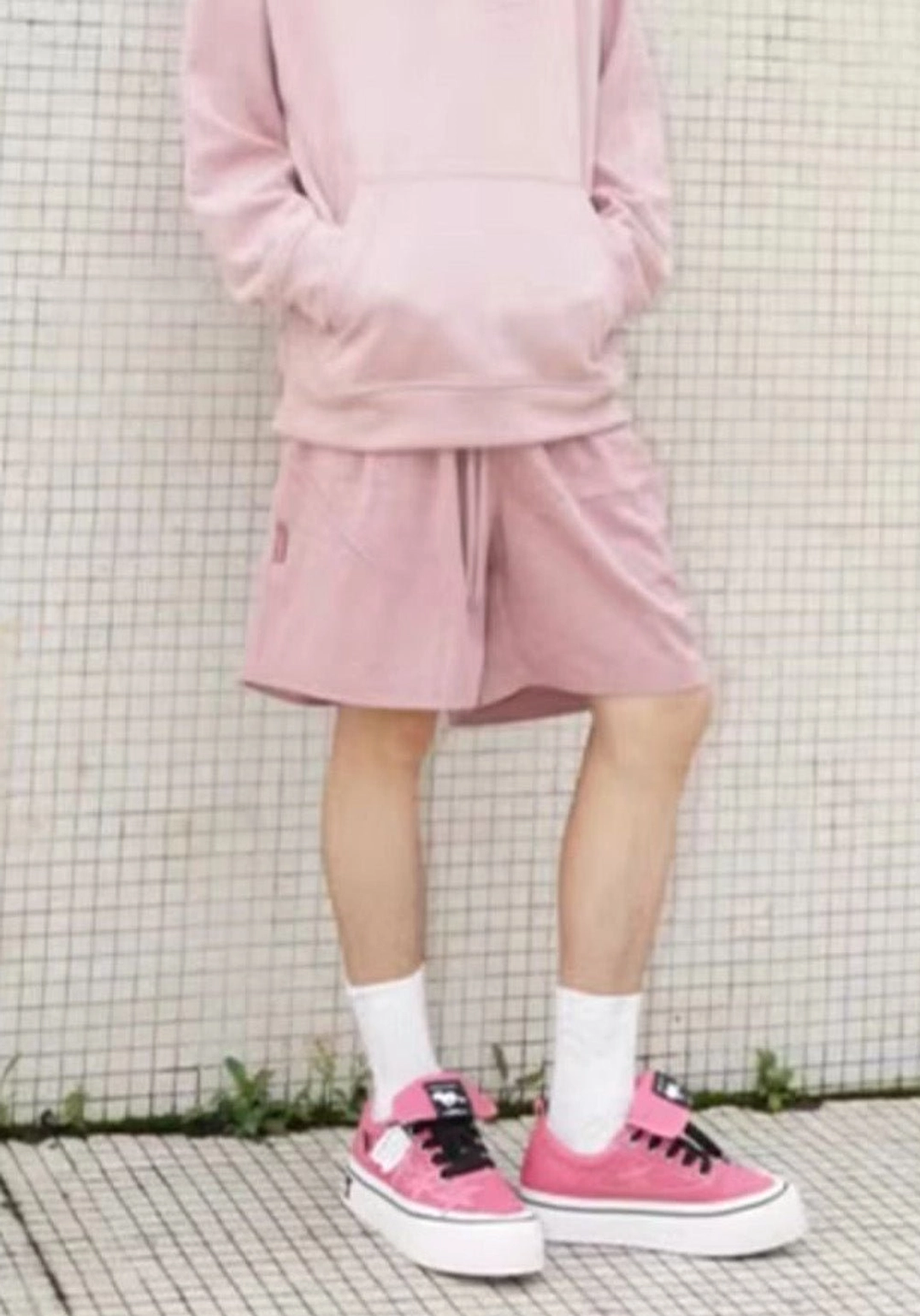 Rose pink star canvas platform sneakers styled on a male model with a matching pink hoodie shorts and white crew socks