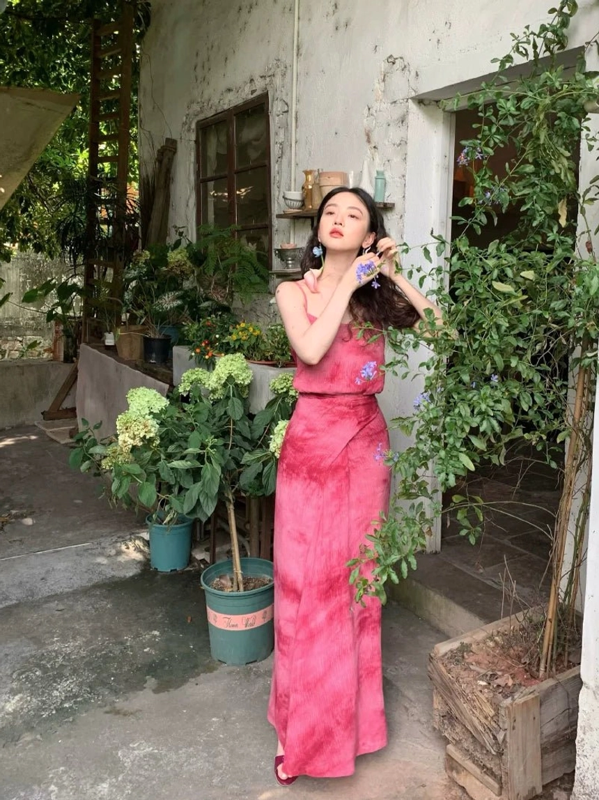 Rose Red tie-dye maxi dress with delicate spaghetti straps, fitted bodice, subtle floral detail, and flowing floor-length skirt outdoors