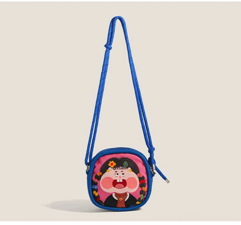 Royal blue cartoon girl mini crossbody bag with pink character print hanging from a rope shoulder strap