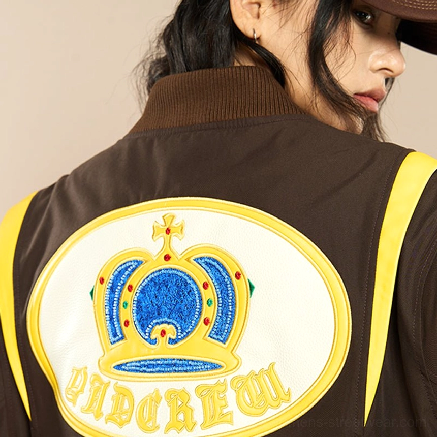 Close up of raised blue royal crown embroidery with yellow green and white details on brown varsity jacket
