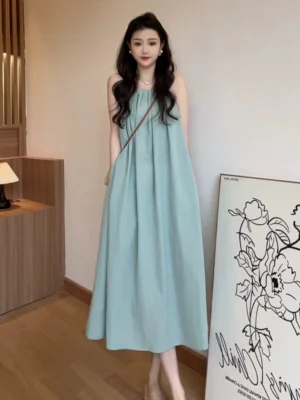 Dusty blue ruched halter neck flowing maxi dress shown from the front on a model with a crossbody bag