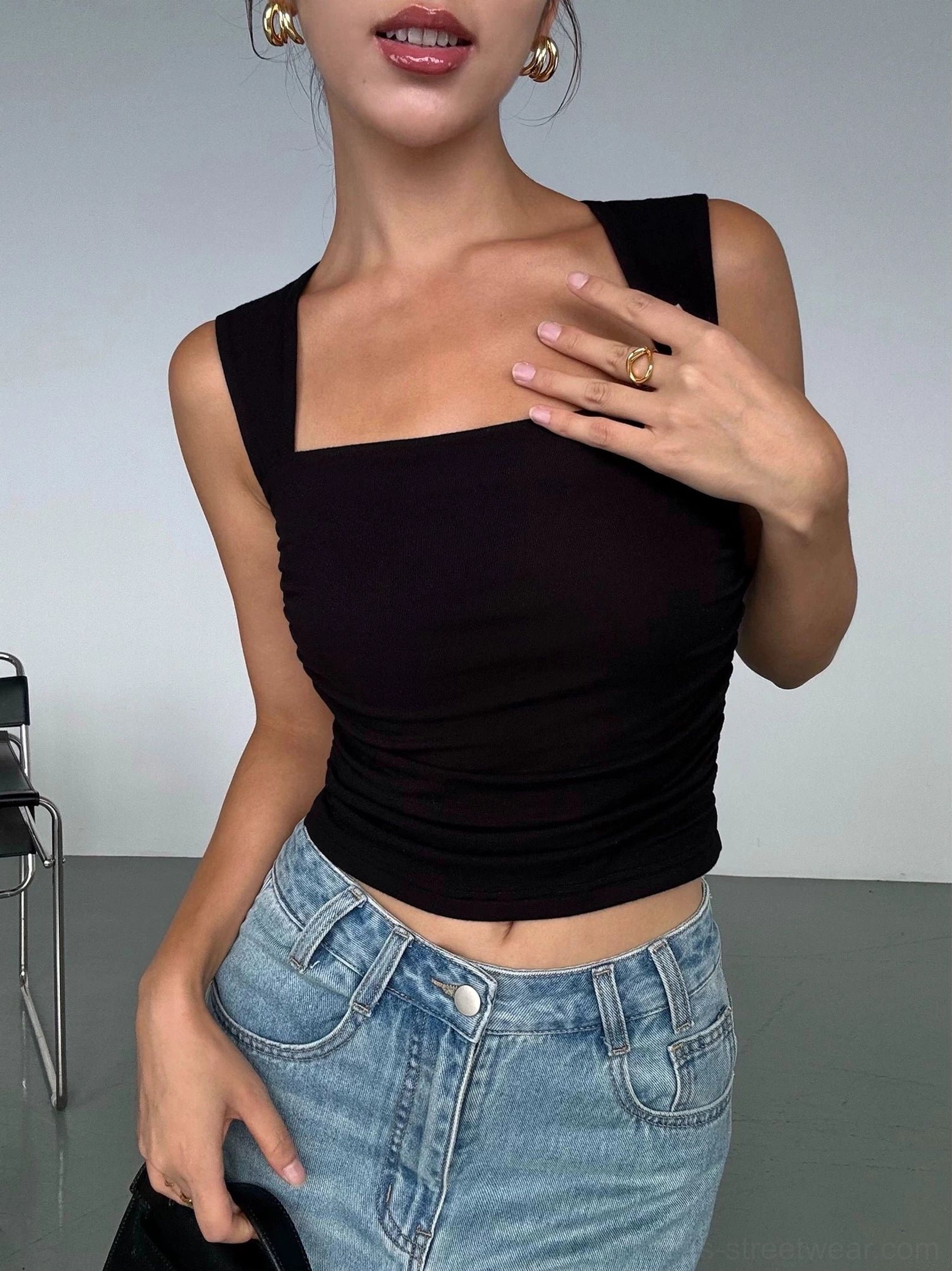 Black ruched square neck cropped tank top styled with high waisted blue jeans in a minimalist studio front view