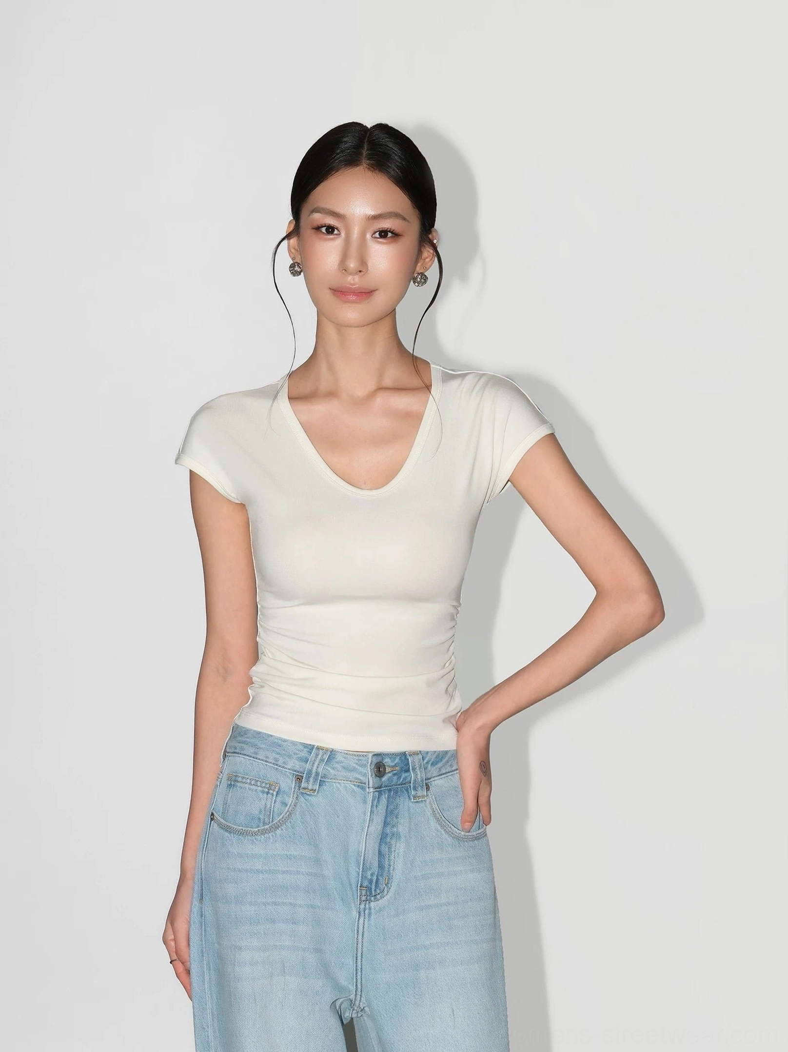 Cream ruched V-neck sculpting knit baby tee for women styled with light wash denim jeans