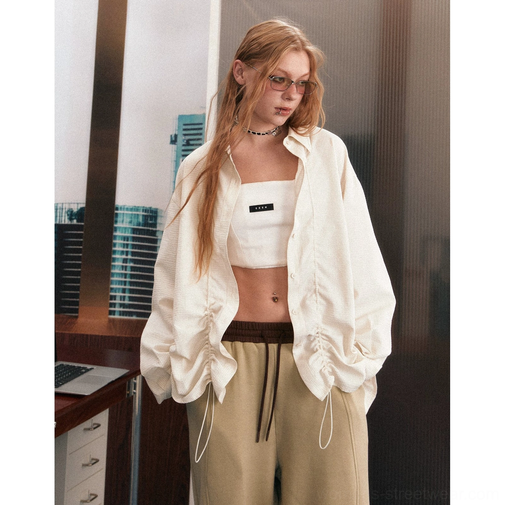 Cream oversized ruffled drawstring shirt styled with a bandeau top and relaxed sweatpants in a retro indoor setting