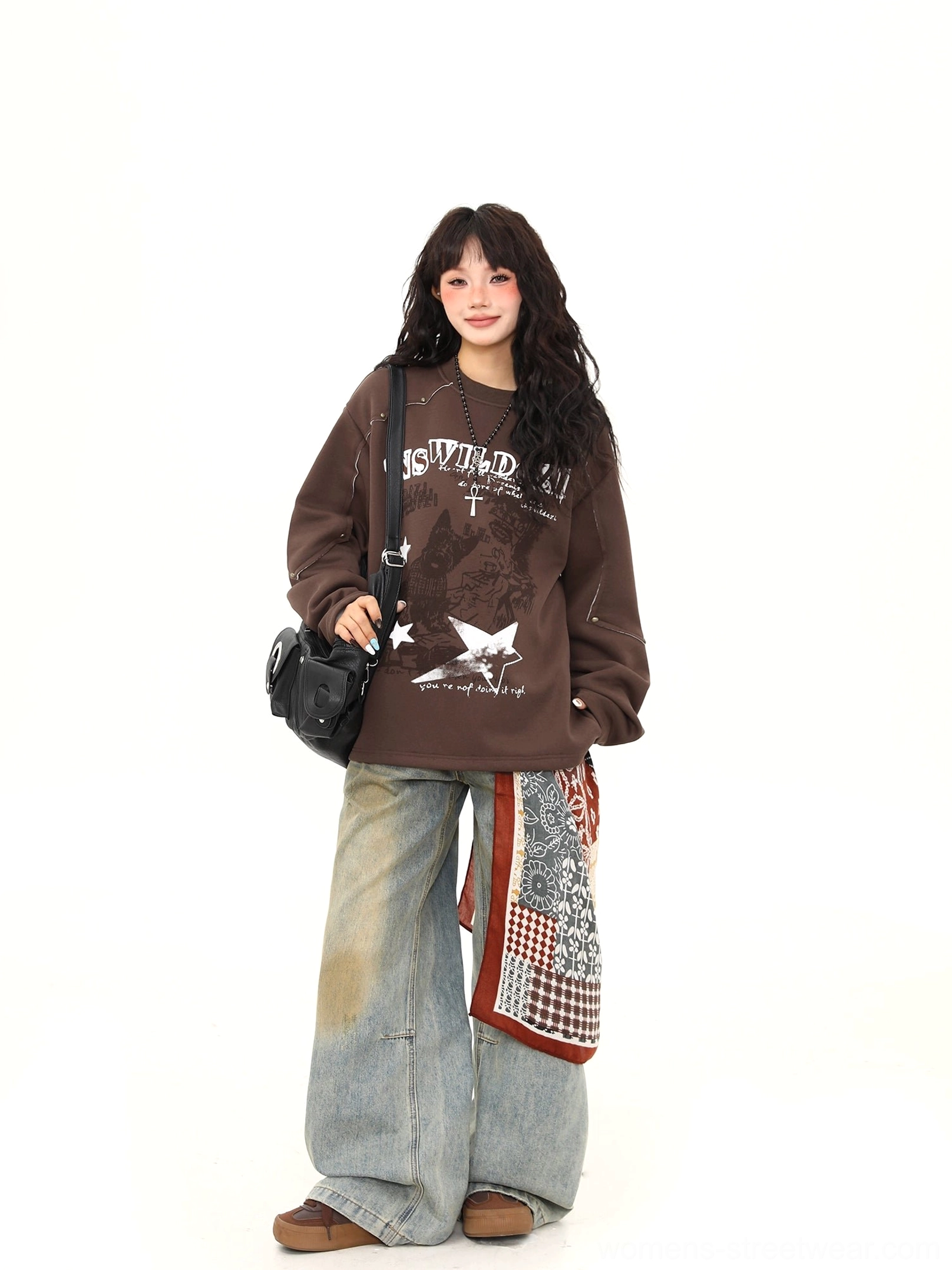 Three-quarter front view of brown vintage punk graphic sweatshirt with relaxed oversized fit and black crossbody bag styling