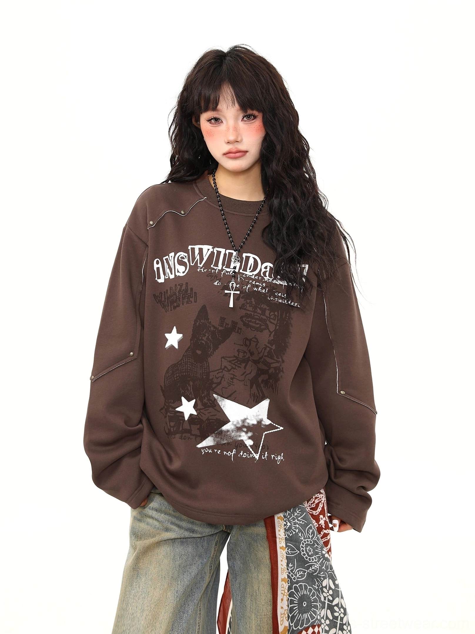 Front full-body view of oversized brown rust rebel distressed graphic crewneck sweatshirt styled with washed wide-leg jeans and printed bandana