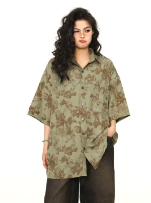 Female model wearing a sage green oversized floral print button-down shirt with brown botanical pattern and dark brown wide-leg pants