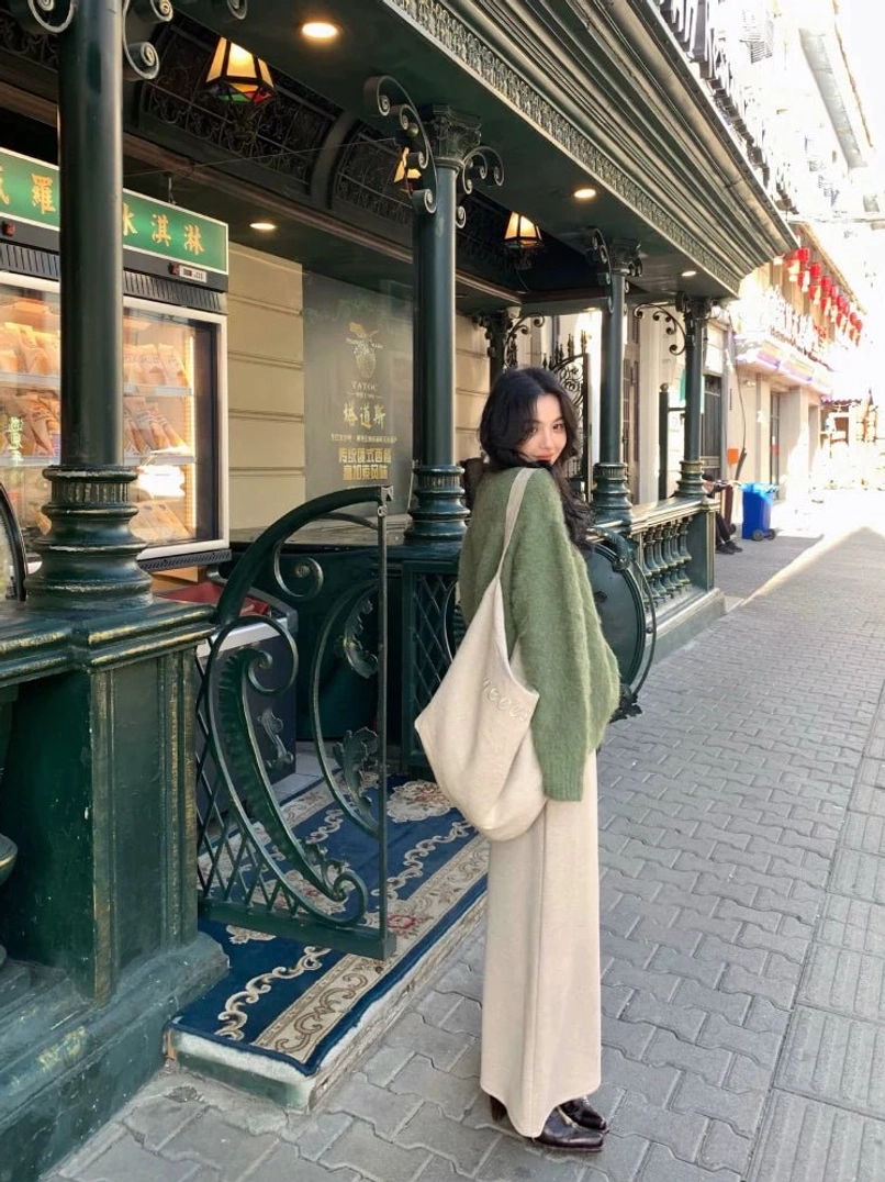 Sage green fuzzy knit sweater shown from the back with dropped shoulders and loose casual fit styled with apricot wide-leg pants and a large canvas tote bag