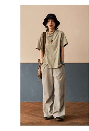 Soft sage green raglan t-shirt with standard crew neck and loose everyday fit, paired with light gray wide leg pants and bucket hat