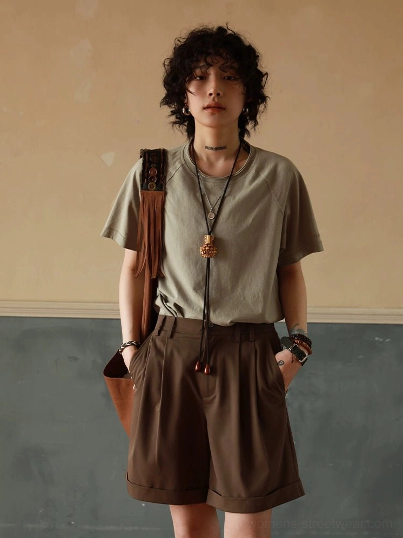 Sage green minimalist raglan t-shirt full body front view, paired with brown tailored shorts and leather pouch for streetwear styling