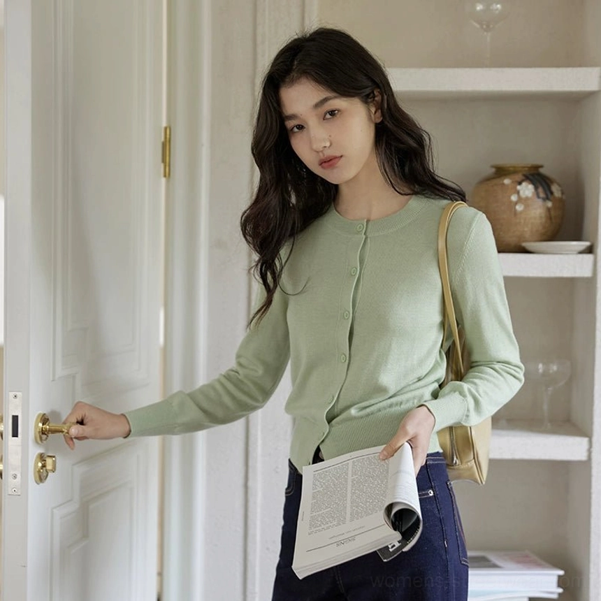 Sage mint green women's classic crew neck button-front cardigan paired with dark wide-leg jeans and a tan shoulder bag