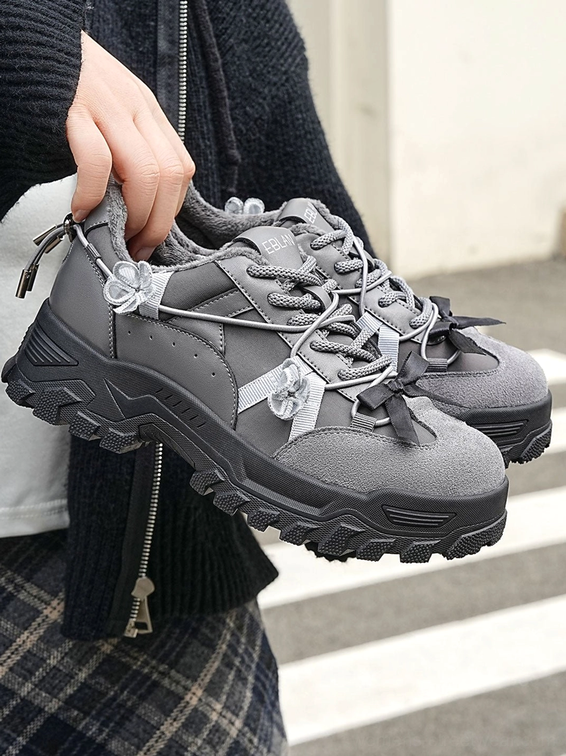 Close up pair of dark grey sakura plush chunky trail sneakers with visible fleece lining decorative flowers deep lug sole and knitwear styling