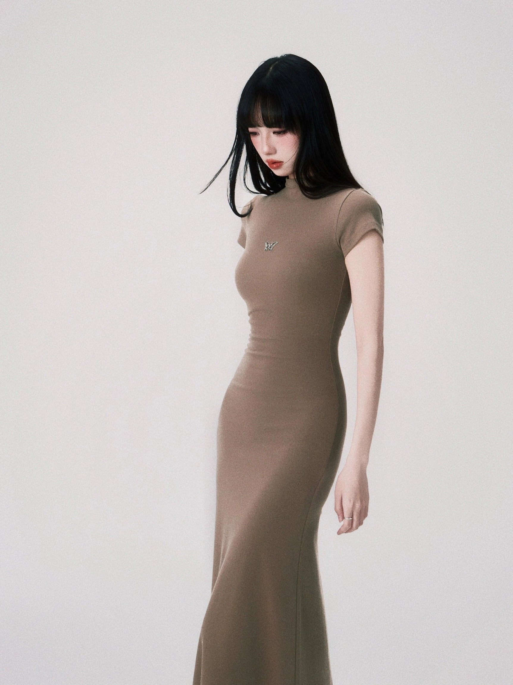 Side view of sand fitted maxi dress showing the sculpted bodycon shape soft matte knit fabric and fishtail hem