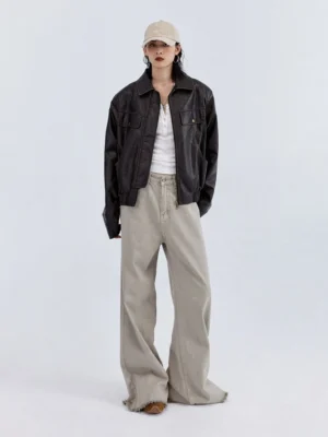 Model wearing sandstone beige wide-leg denim jeans with a white tank top leather jacket and baseball cap