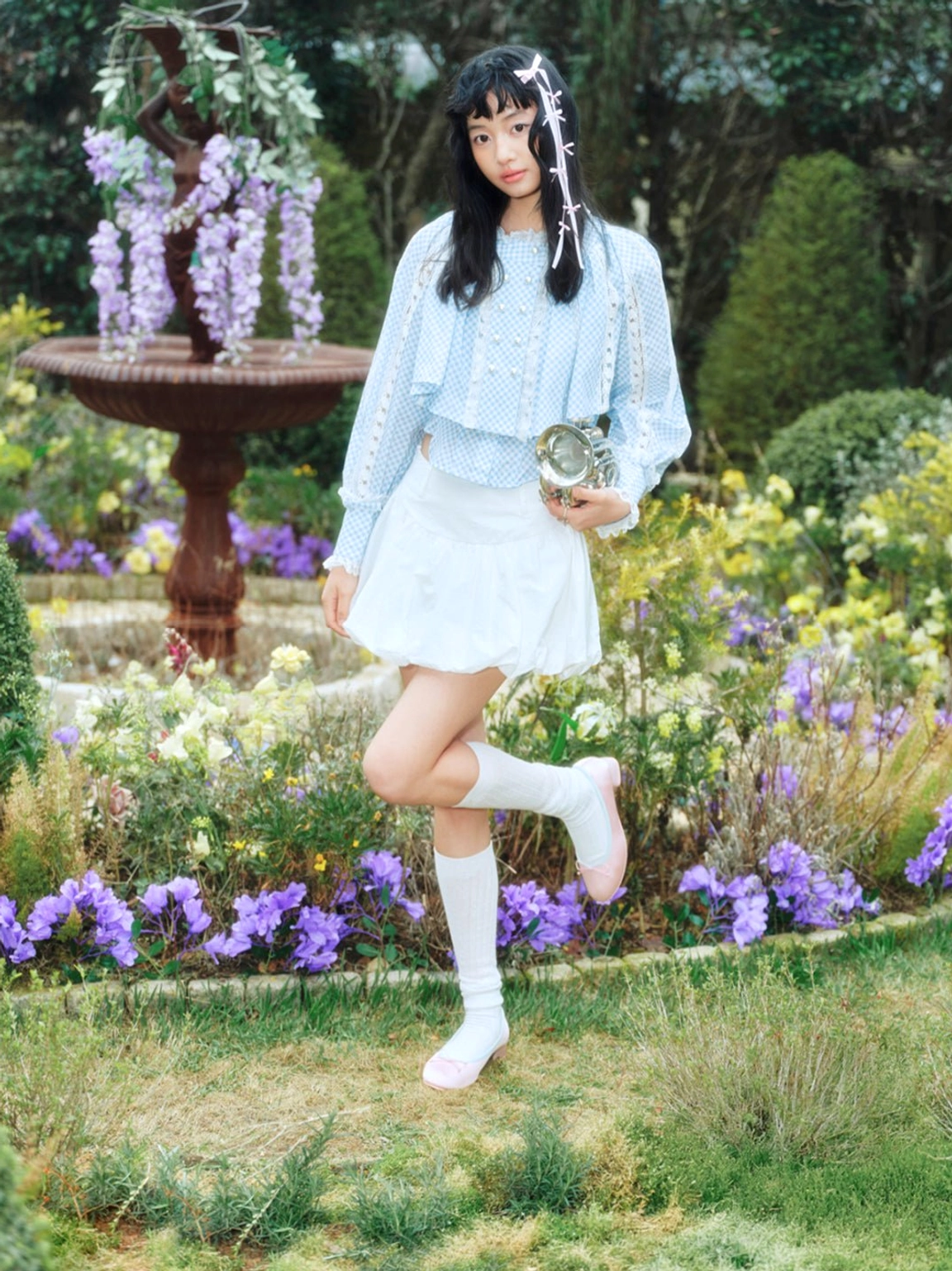 Model styling pink satin bow low block heel ballet pumps in a wisteria garden Seoul preppy look