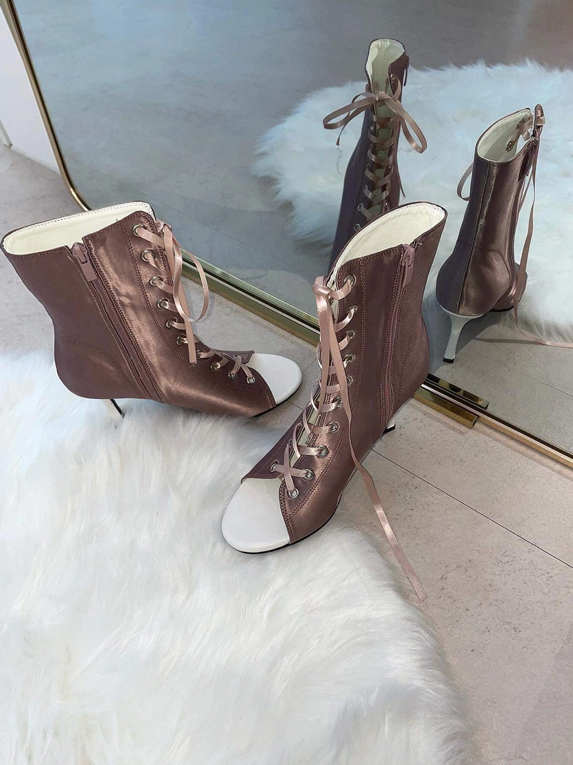 Multiple satin lace-up peep-toe ankle heels in dusty rose and light pink arranged on a soft fur mat