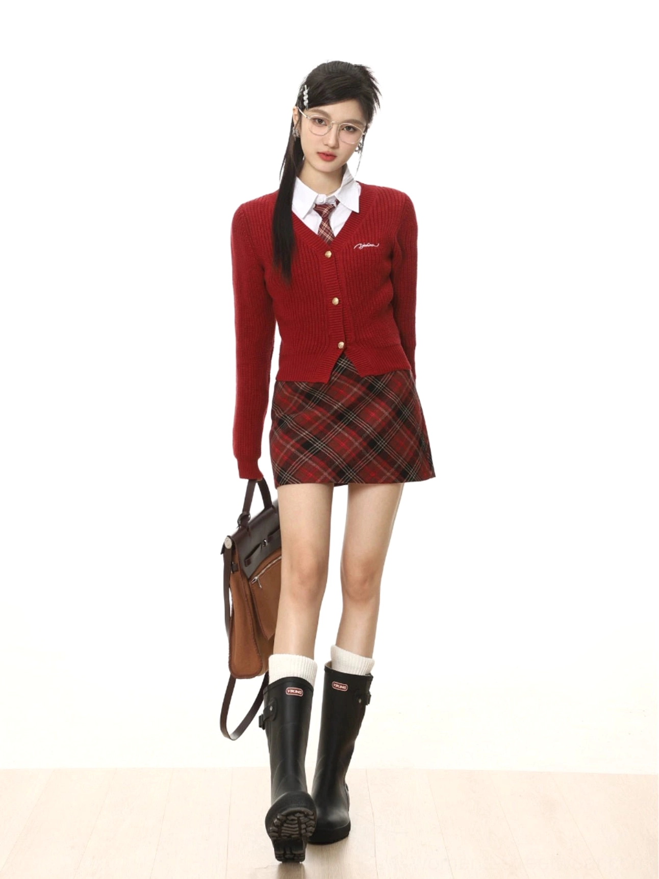 Front walking view of scotch red high-waisted tartan plaid mini skirt styled with black boots and a leather handbag