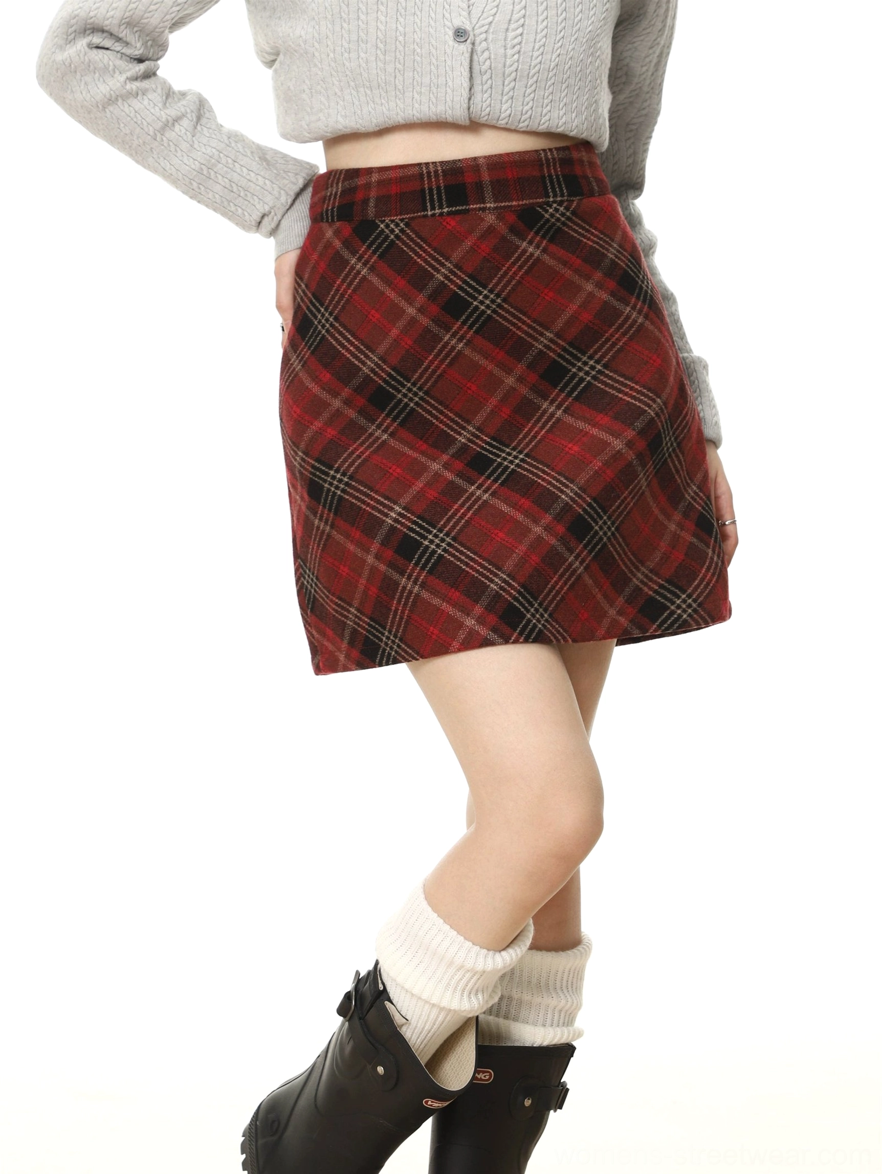 Side detail view of scotch red tartan plaid high-waisted mini skirt paired with gray knit top white socks and black boots