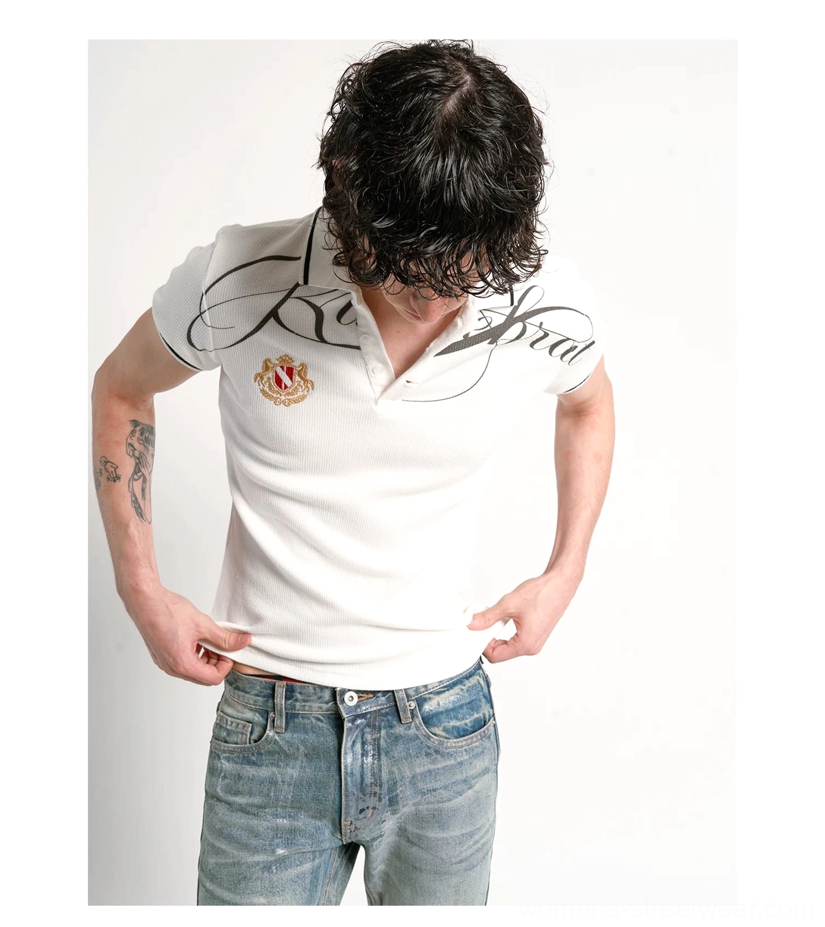 Close-up detail of black cursive chest print and embroidered crest on white cotton pique polo shirt
