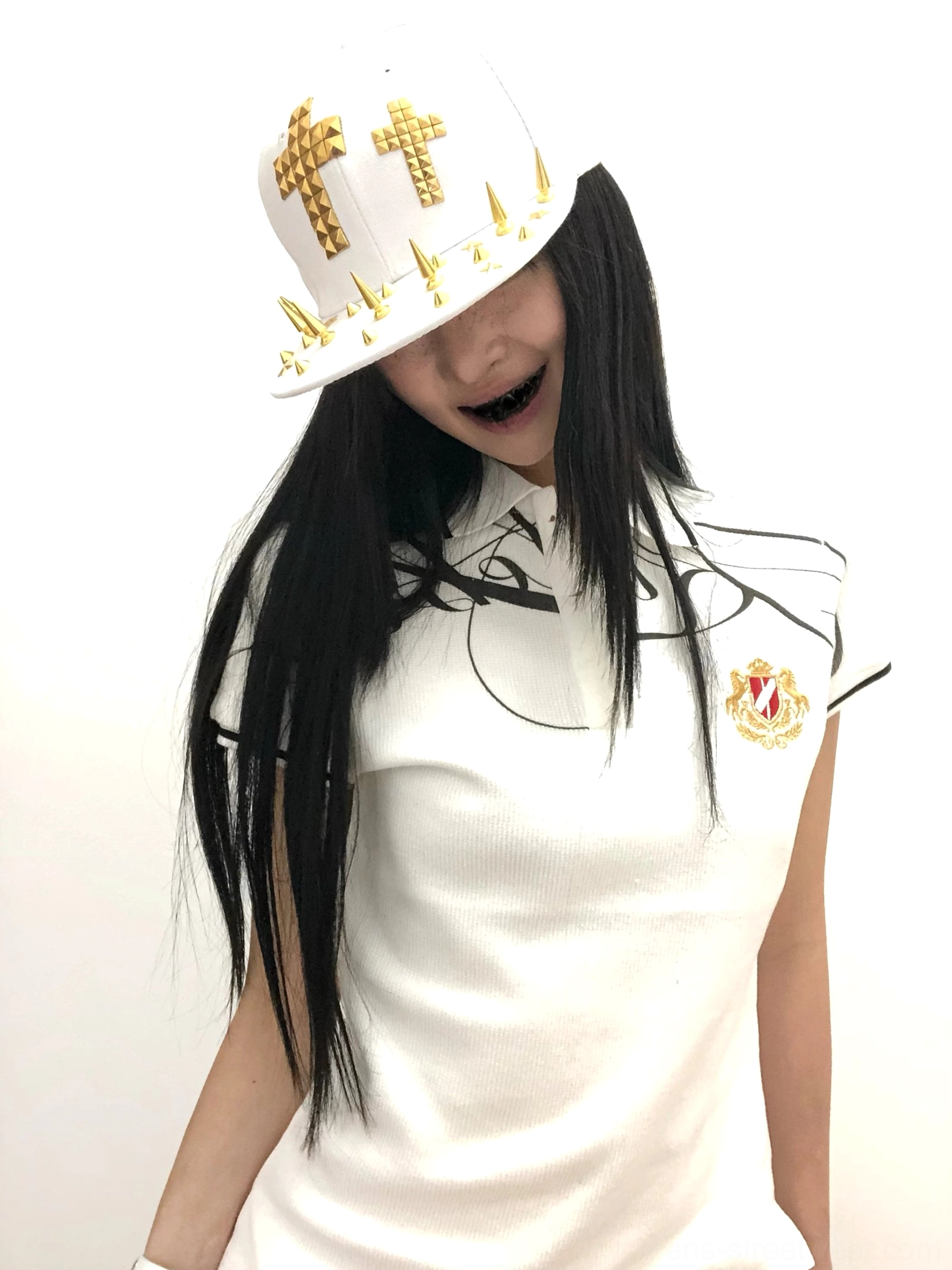 Female model wearing white script crest pique polo shirt with black calligraphy print embroidered crest and contrast collar