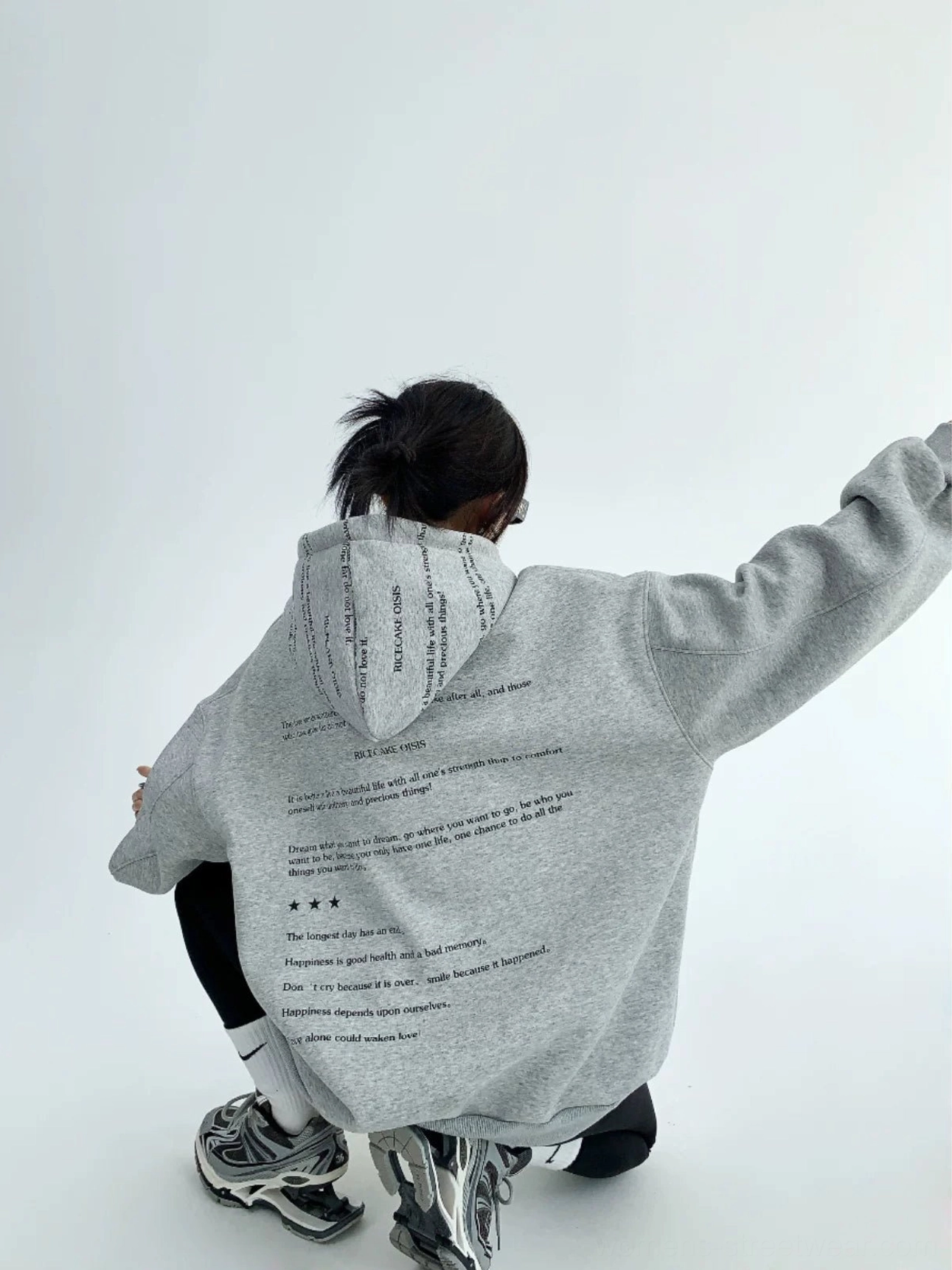 Heather gray oversized graphic fleece hoodie low angle back view showing vertical script print across hood and back