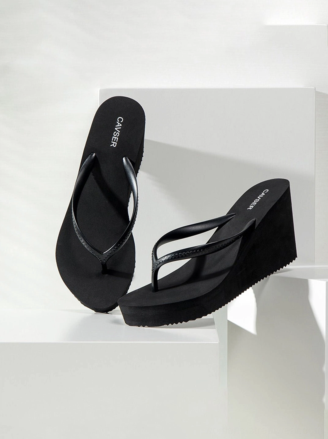 Angled top view of black sculpted high-wedge flip-flops with sparkling toe-ring straps