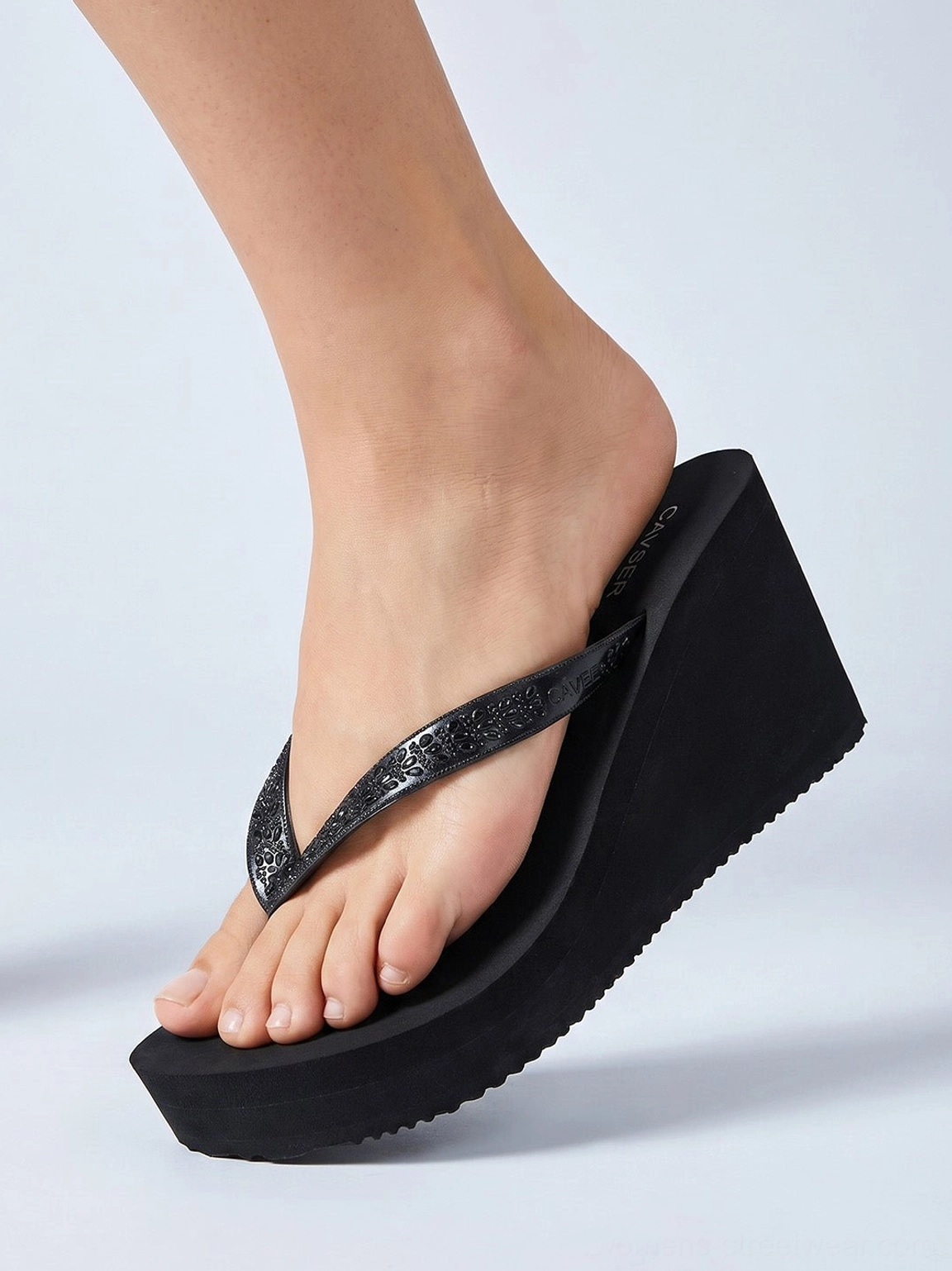 Black high platform wedge toe-ring flip-flops worn on feet, showing the elevated glitter strap fit