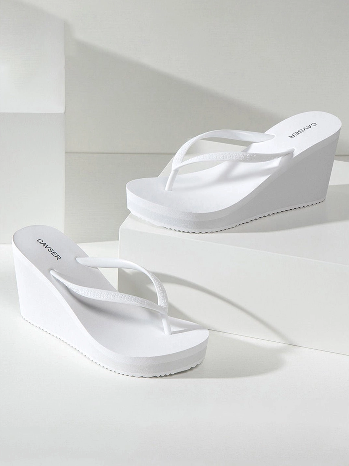 Sculpted high-wedge toe-ring flip-flops showing the curved platform sole and rubber construction