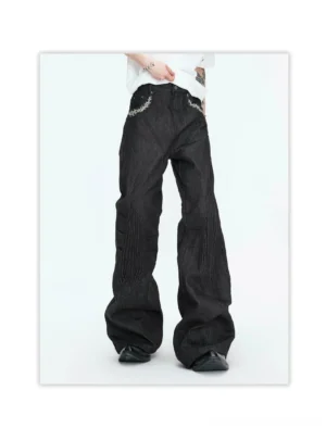 Front view of oversized wide-leg black denim jeans with curved panel seams, contrast topstitching, embroidered pocket details, and elongated streetwear silhouette