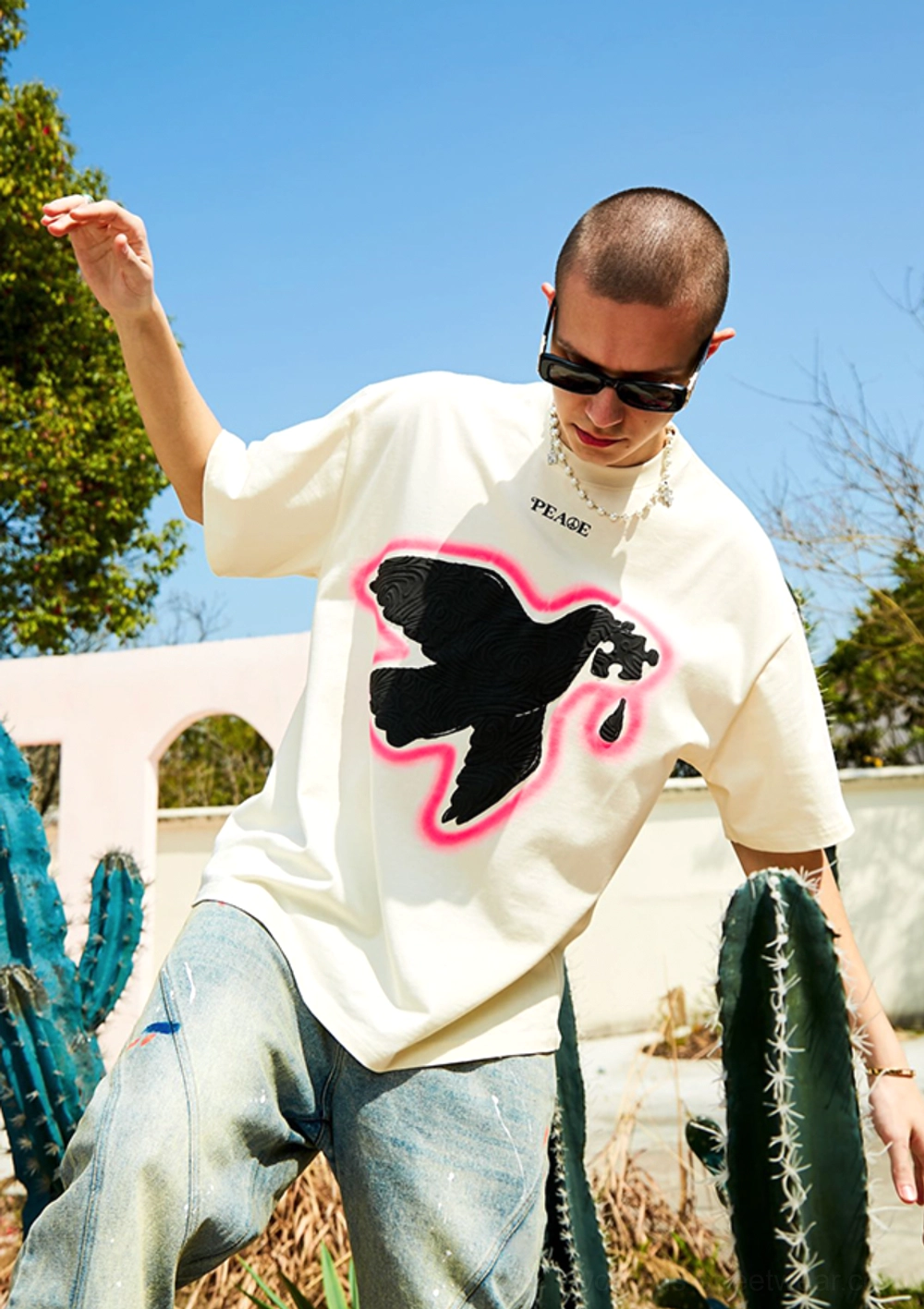 Male model in sunglasses wearing Serene Dove oversized suede foam print T-shirt in outdoor desert inspired setting