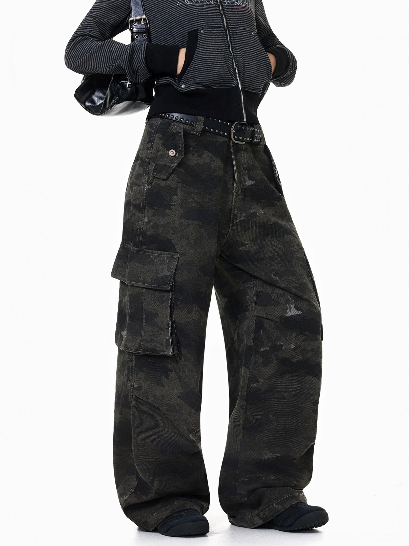 Dark washed camouflage baggy cargo pants styled with a striped cropped top, studded belt, black crossbody bag, and casual streetwear accessories