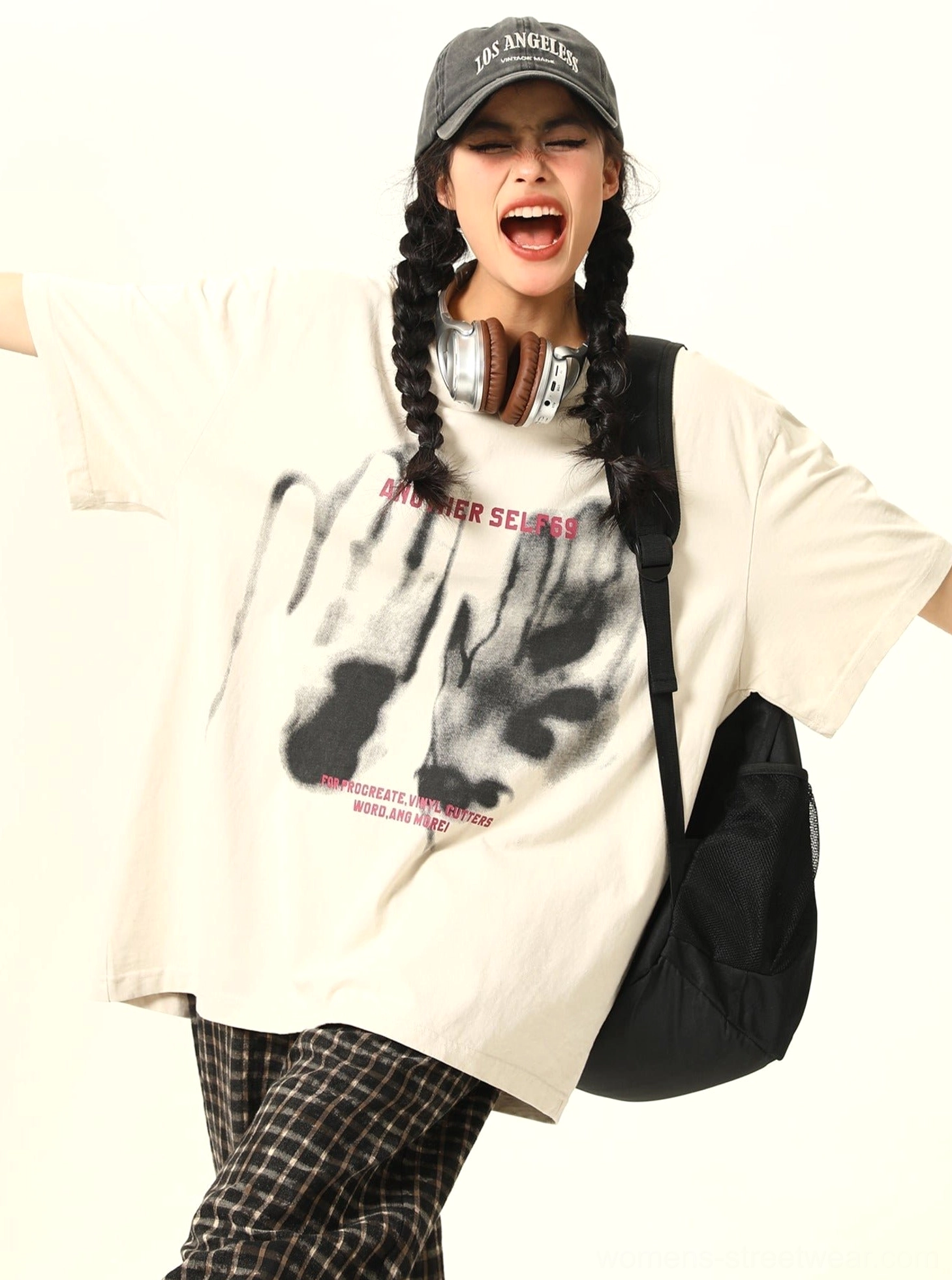 Apricot oversized graphic streetwear T-shirt showing relaxed drape and bold shadow hand artwork with vivid pink lettering in a playful selfie-inspired outfit