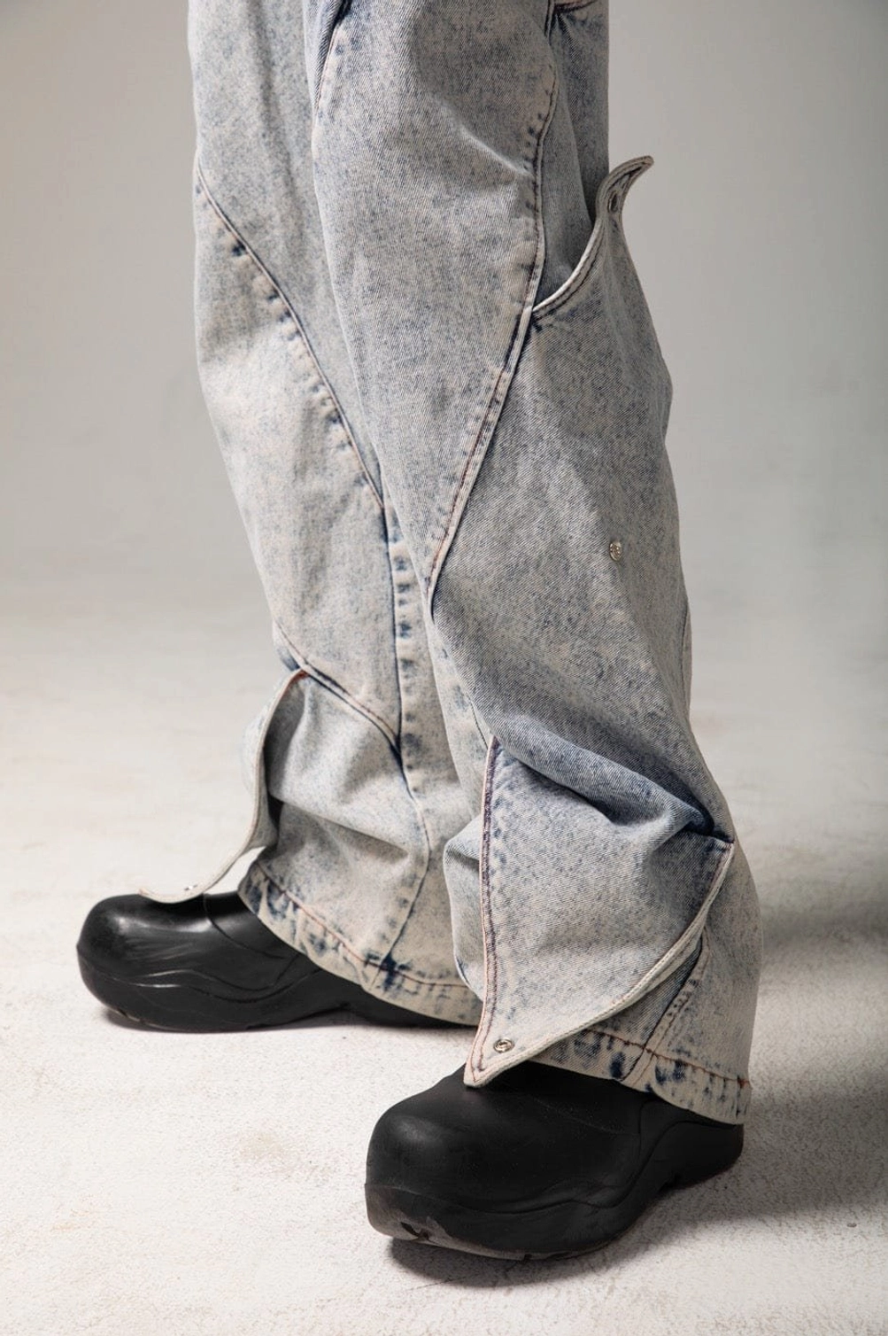 Close-up of shark fin baggy jeans hem showing flared panel construction, denim stitching, and chunky shoe styling