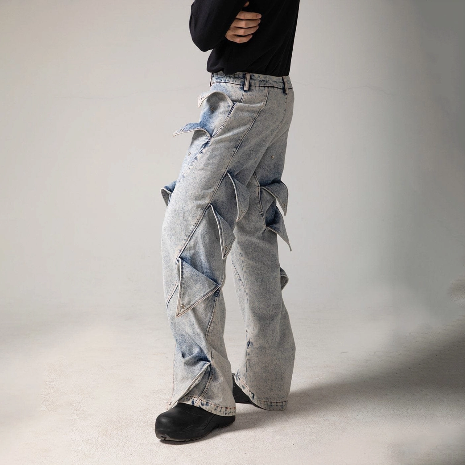 Right side view of light blue shark fin panel jeans with asymmetrical thigh details and wide flared leg opening