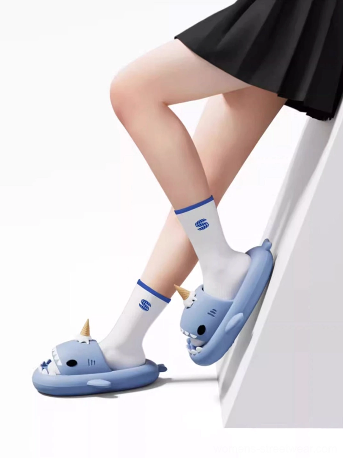 Model wearing playful shark platform slides with socks and a school-inspired streetwear skirt outfit