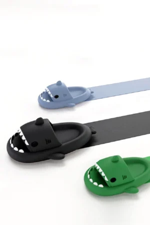 Shark slide slippers in light blue, black, and green colorways with shark fin details and playful streetwear-inspired styling